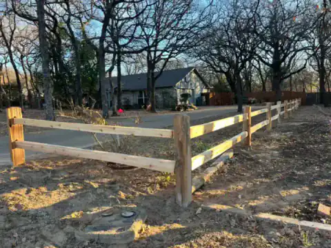 Horizontal rail fence borders a wooded North Texas property.