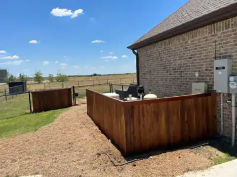 Warm cedar privacy fence encloses a brick home's back patio.