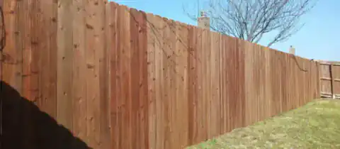 Cedar privacy fence stretches across an open residential lot.