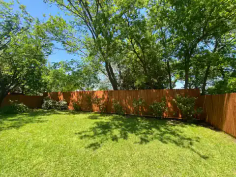 Cedar privacy fence borders a broad grassy backyard.