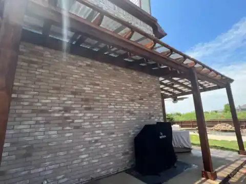 Cedar pergola extends from a brick home over the patio.