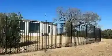 Black metal fence encloses an open North Texas property.