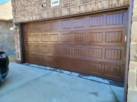 Brown carriage-style garage doors set into a brick facade.