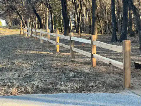 Split-rail wood fence winds through a wooded property.