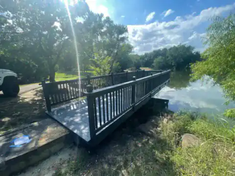 Black-railed footbridge crosses a pond near a backyard.