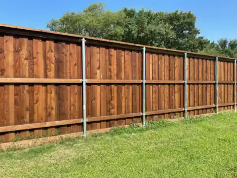 Cedar fence with galvanized metal posts borders a lawn.