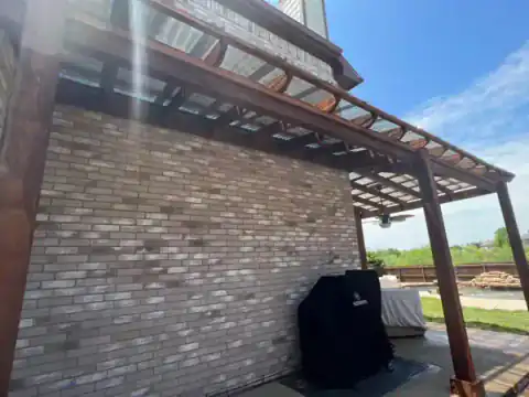 Cedar pergola attaches to a brick home over the patio.