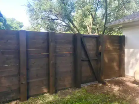 Dark-stained cedar gate closes a residential backyard.