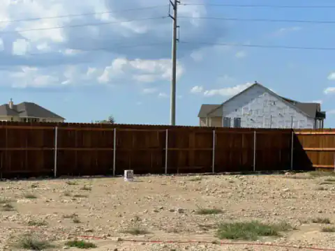 Cedar privacy fence encloses an open residential lot.