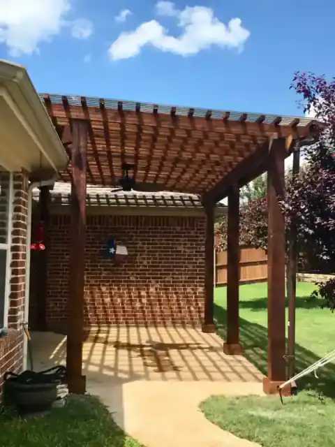 Cedar pergola extends from a brick home over the patio.