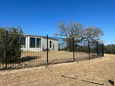 Black metal fence encloses a large open property.