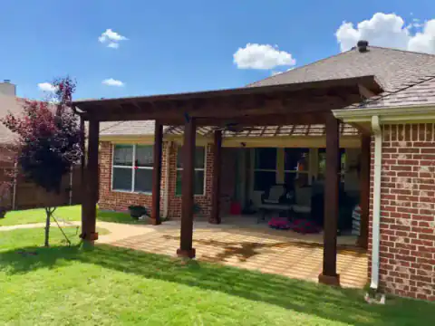 Cedar pergola shades a brick home's backyard patio.