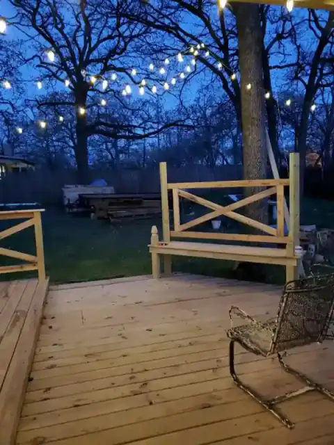 Cedar deck with crossbuck railing glows under string lights.