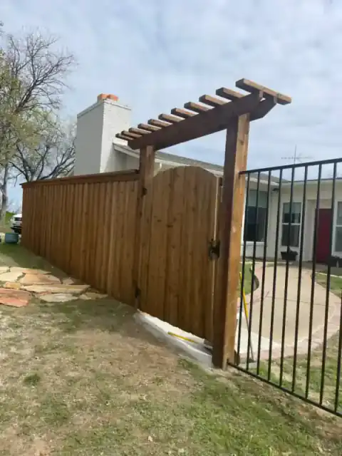 Cedar pergola and black metal gate secure a side entry.