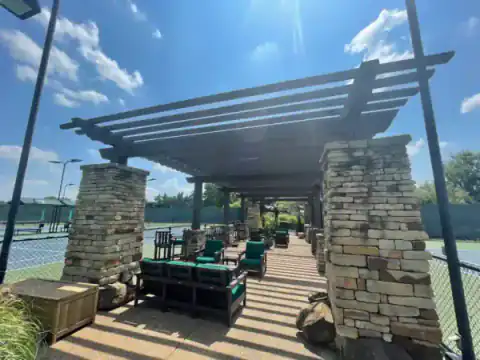 Stone-column pergola shelters a raised wood deck.