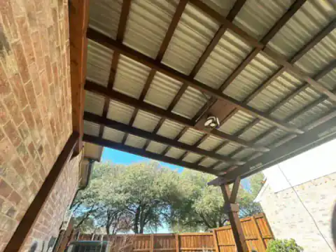 Metal-roof patio cover shelters a residential walkway.