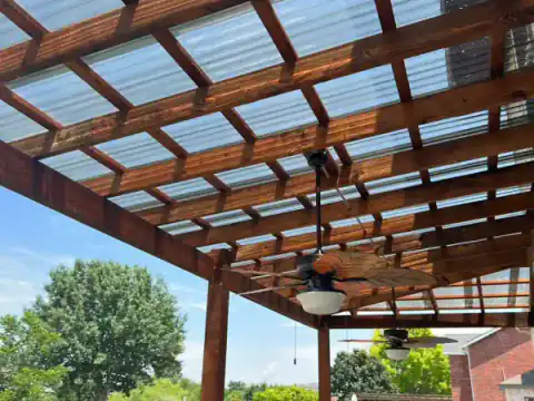 Completed cedar pergola with a translucent roof shading a backyard patio