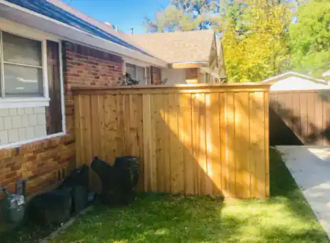 Cedar side gate with black hardware beside a brick home.