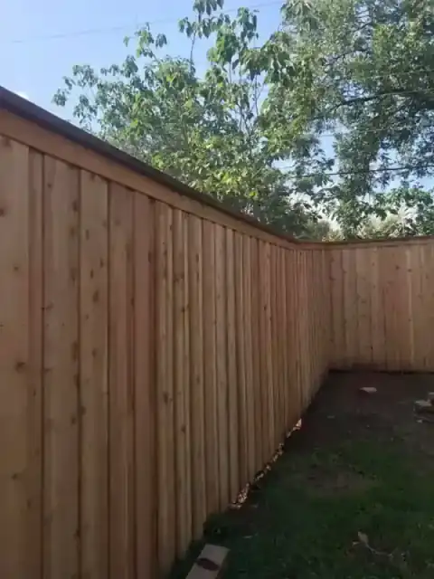 Long cedar privacy fence borders a residential lawn.