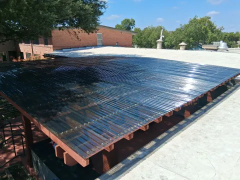 A custom commercial patio cover with a translucent corrugated roof system supported by stained lumber framing.